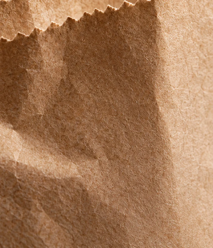 Detalle editorial de la textura y la boca de un cambucho de papel kraft